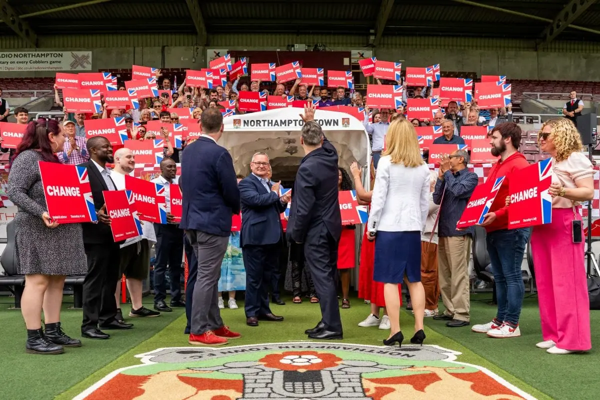 Labour Party supporters holding red "Change" signs at a 2024 UK Election rally at Northampton Town football club.