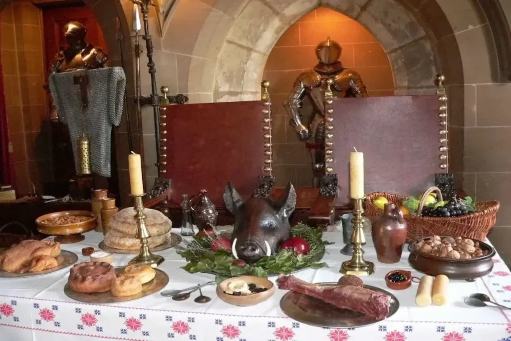 A medieval-style Christmas feast table featuring a boar's head centerpiece, traditional pies, bread, and fruits in a stone castle setting with knight armor.